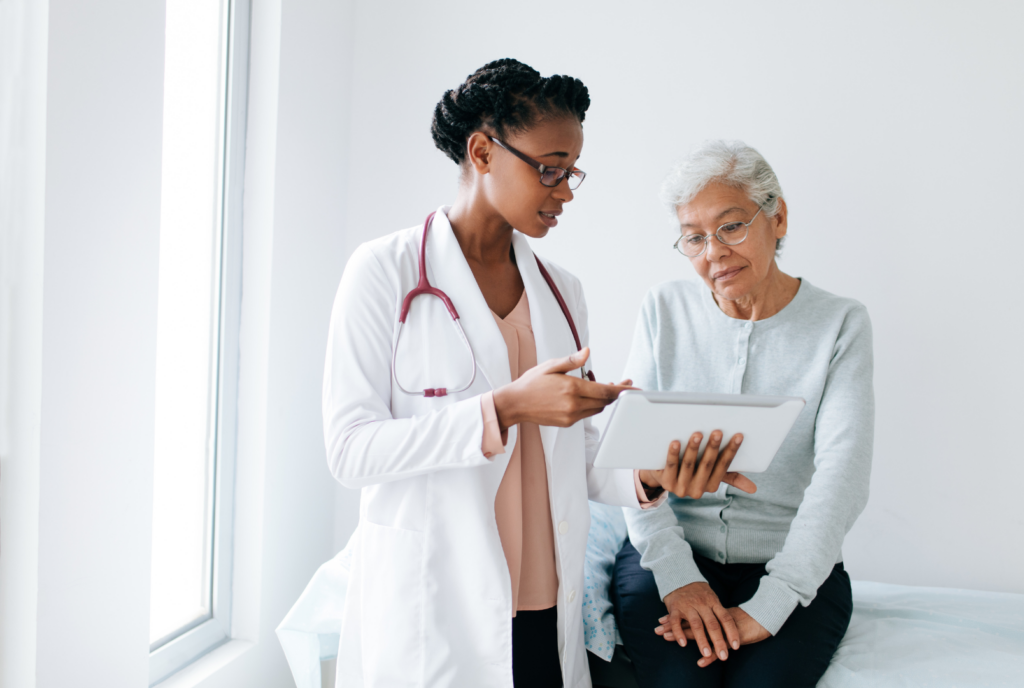 A female doctor in a white coat is talking to a female patient advocate
