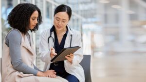 A female doctor is showing a female patient something on a tablet
