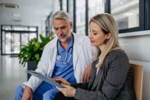 A female Medical Science Liaison is sitting with a male doctor, showing him scientific data on a tablet